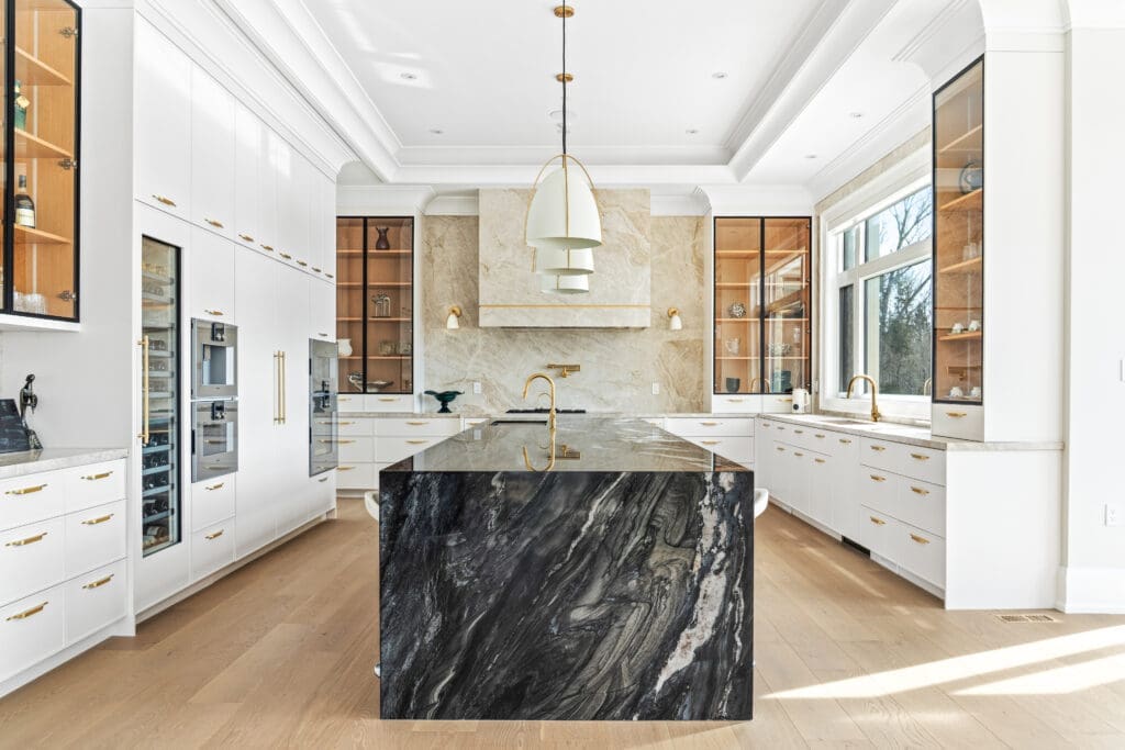 A modern kitchen with light Taj-Mahal quartzite countertop and black Black Tempest island
